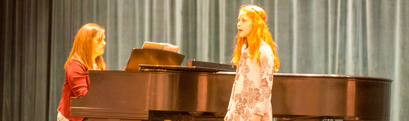 Child singing with pianist accompanying her