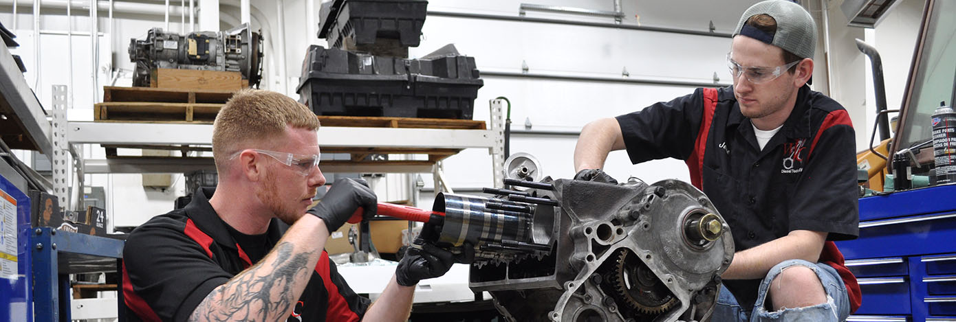 Two diesel tech students work on an engine project.
