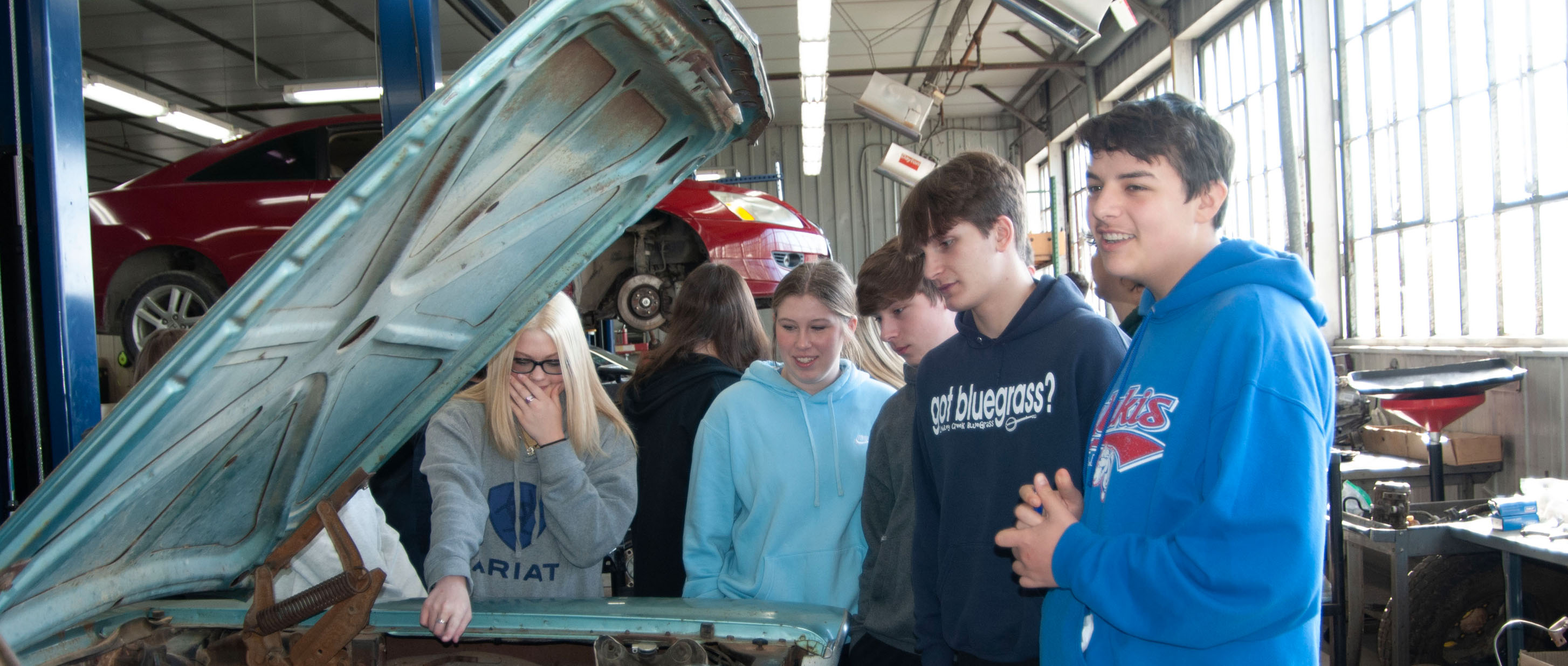 Photo of students looking at a car engine