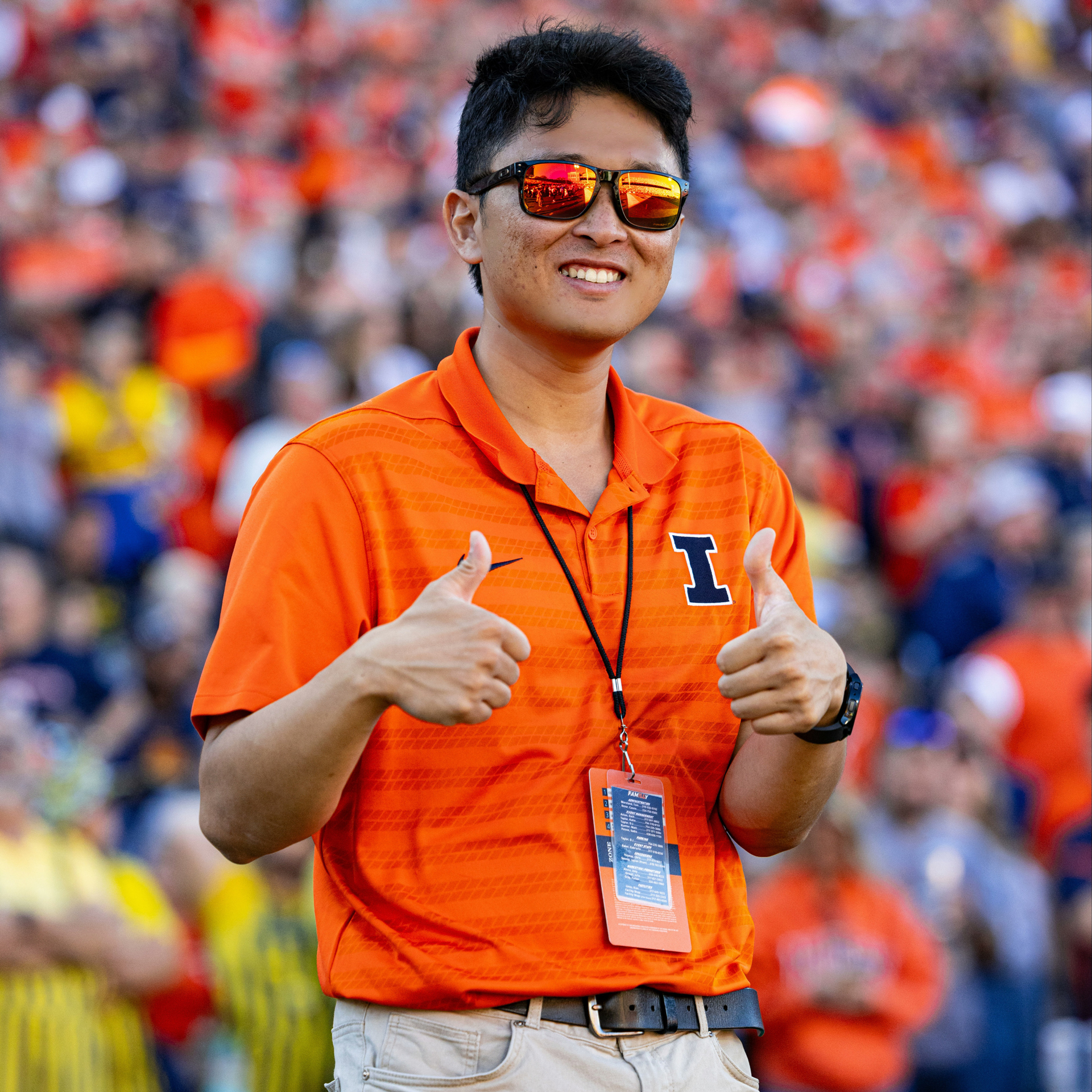 An image of Cy Yun working at a University of Illinois Football game. He's on the field and giving two thumbs up.