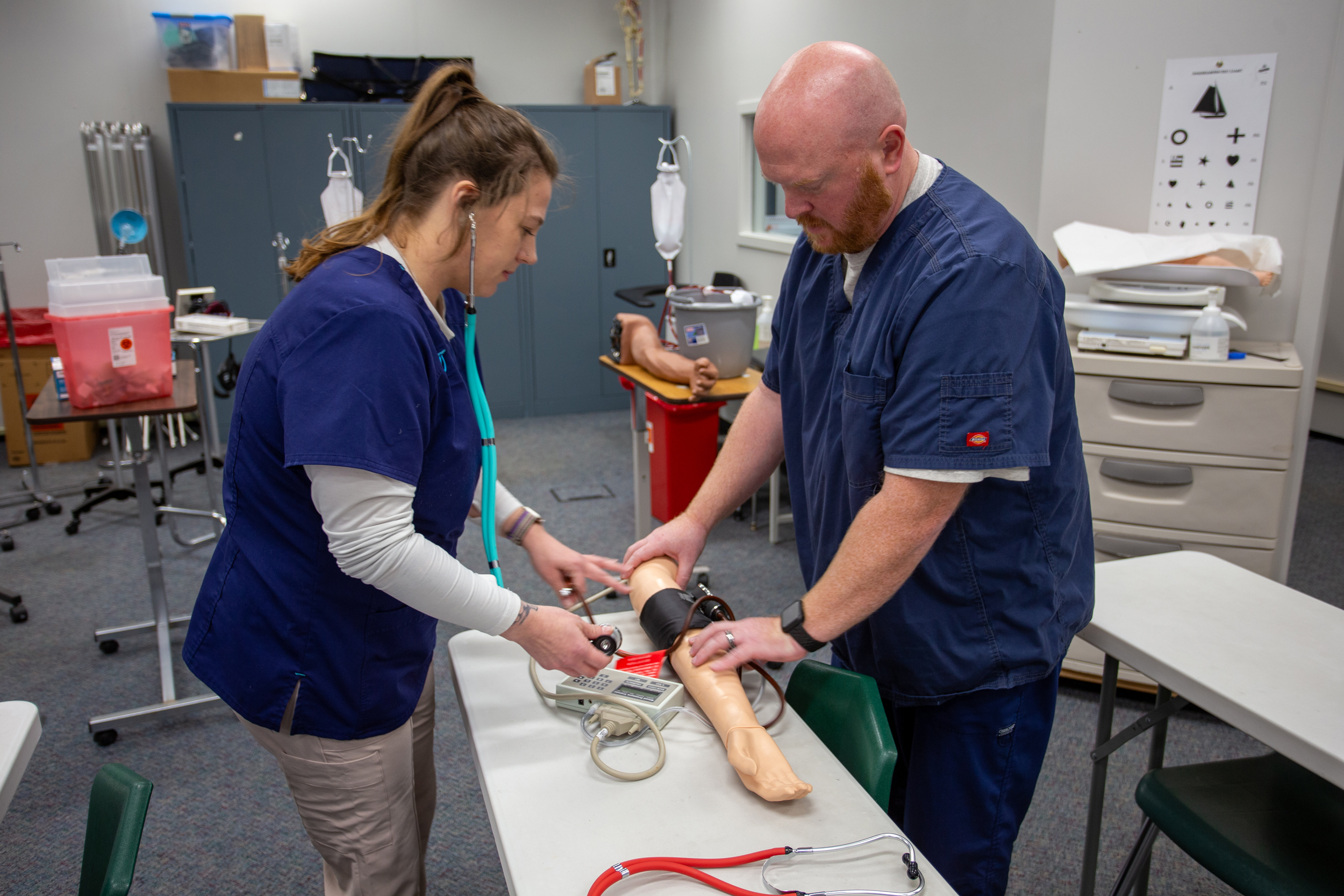 Lincoln Trail College Health Careers Instructor Dr. Jared Gullett demonstrating how to take blood pressure with a student.