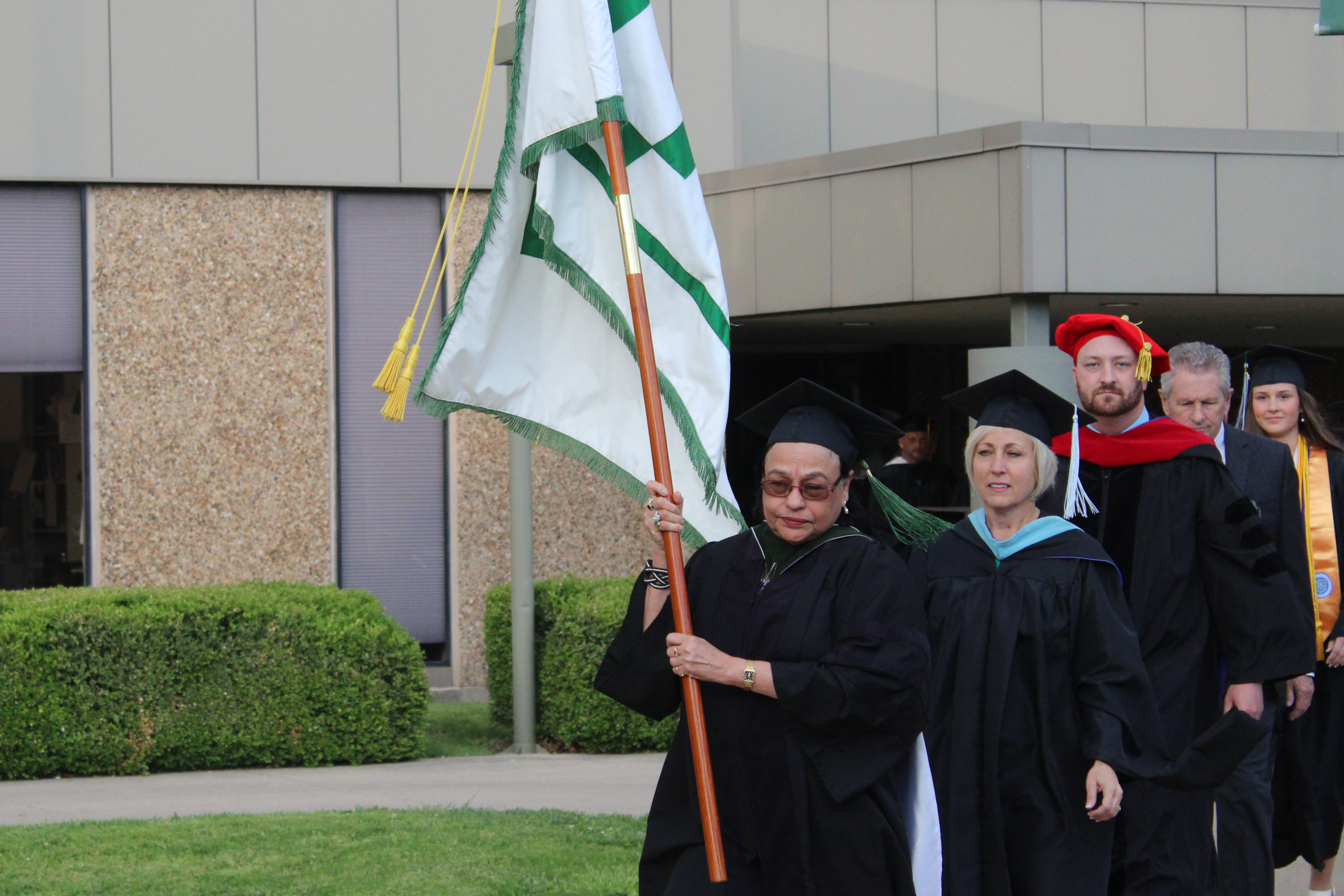 Dr. An Roy leads the procession as the gonfalon bearer during Lincoln Trail College's 54th Annual Commencement. Dressed in academic regalia, faculty, staff, and graduates follow in a proud display of tradition and achievement.