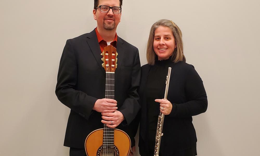 Michael Patilla holding a guitar with Sophie Kershaw-Patilla holding a flute