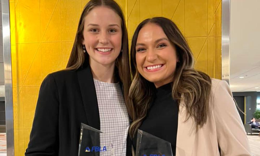 Krista Phillips (left) and Madisyn McIntosh (right) celebrate by holding their 6th place trophies at the FBLA Collegiate National Leadership Conference