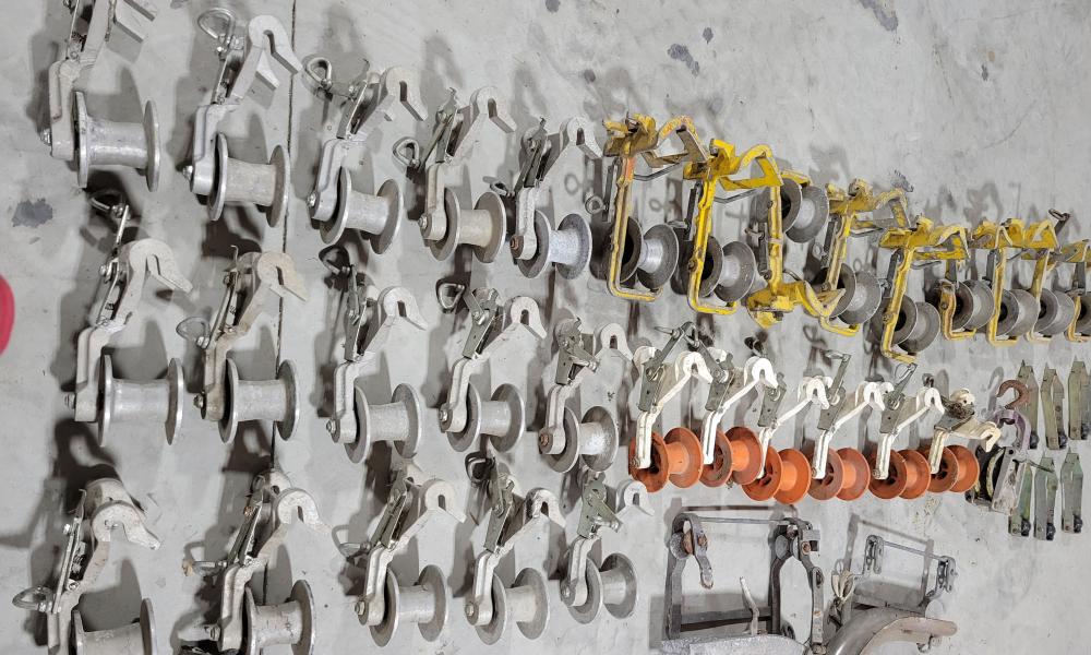 Cable rollers, cable blocks, and over-lash guides laid out on a concrete floor, part of a donated equipment set for Lincoln Trail College’s Broadband Telecom program.
