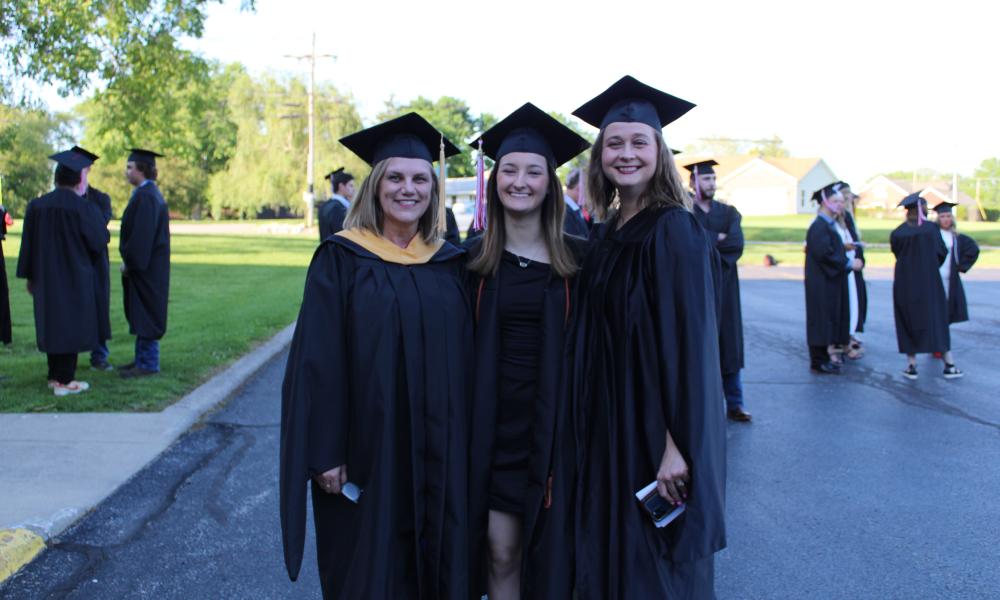 WVC Graduate (centered) and two instructors pose in parking lot