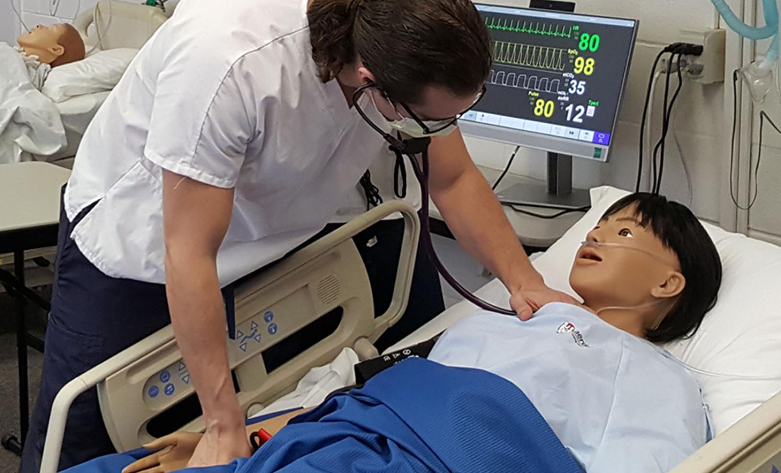 Photo of OCC Nursing Student Listening to Manikin's Heart Beat
