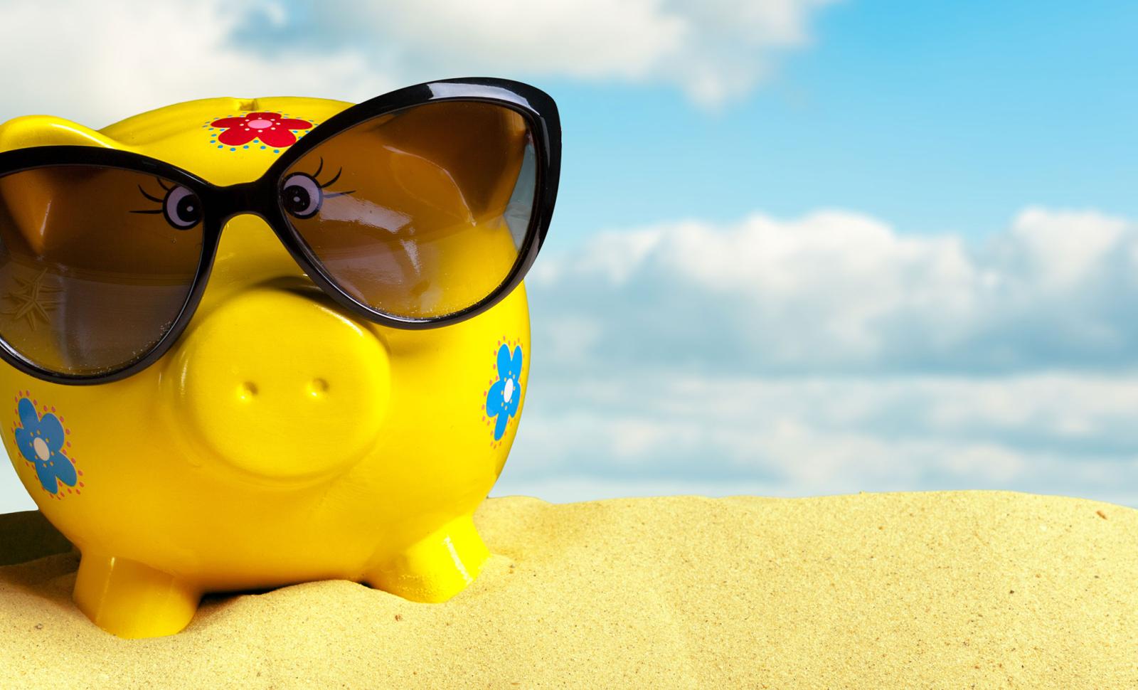 Piggy bank on the beach wearing sunglasses