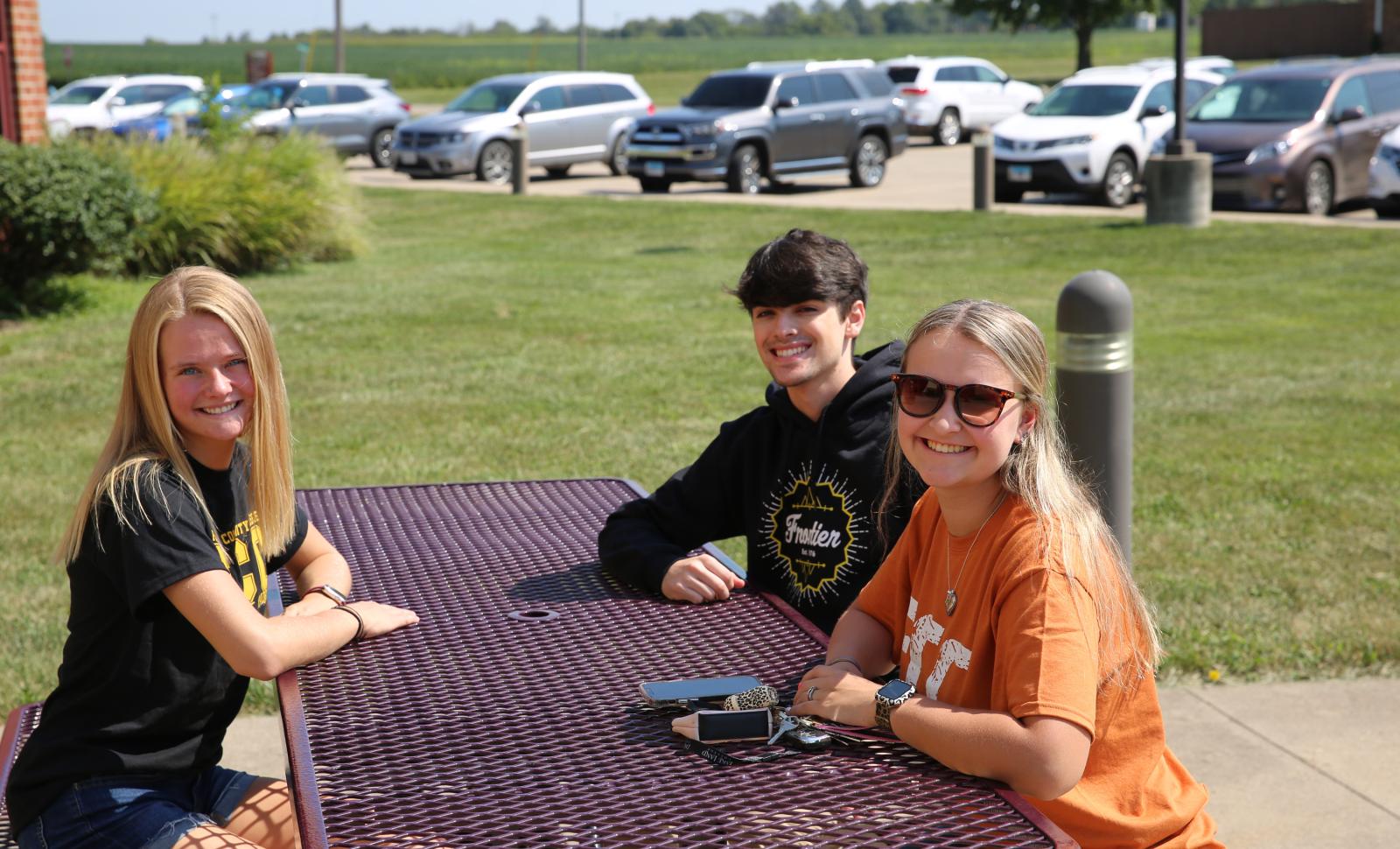 Friendly Frontier Community College students sitting around a picnic table smiling