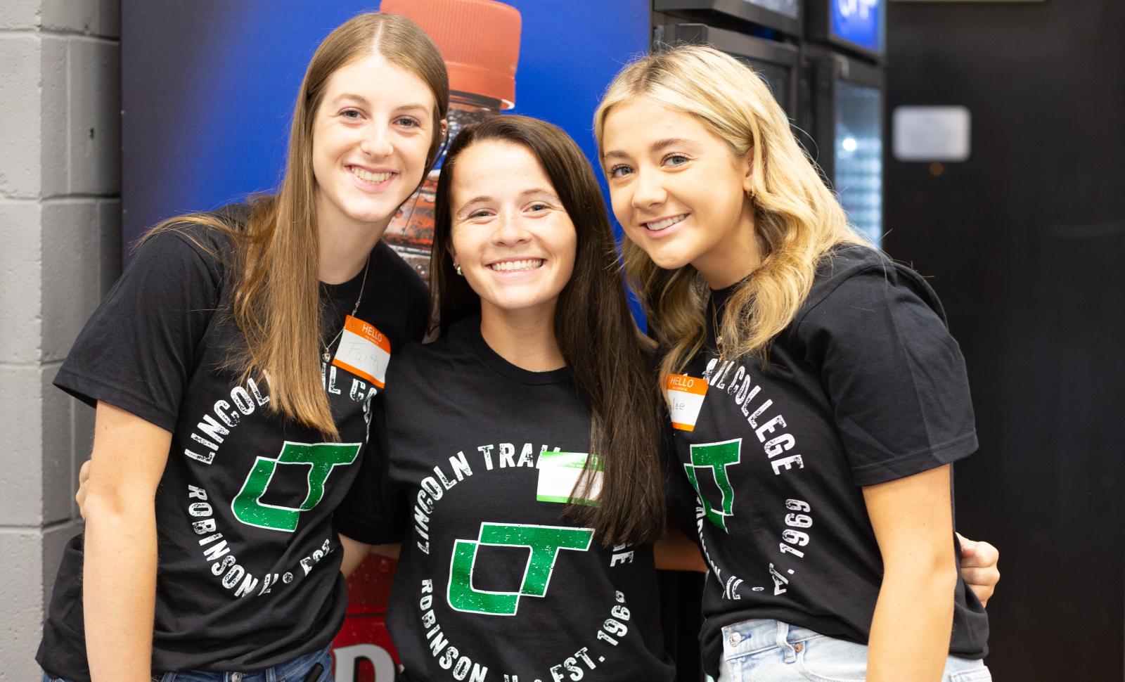 Three smiling Lincoln Trail College students wearing Lincoln Trail College T-shirts hugging and posing for a photo.