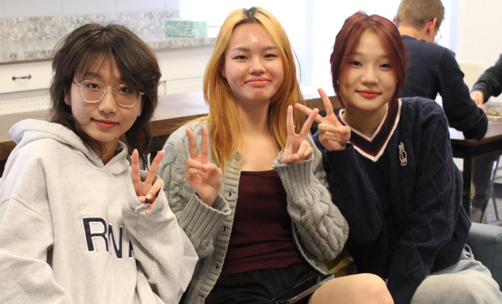 3 students pose for camera with peace signs in the air