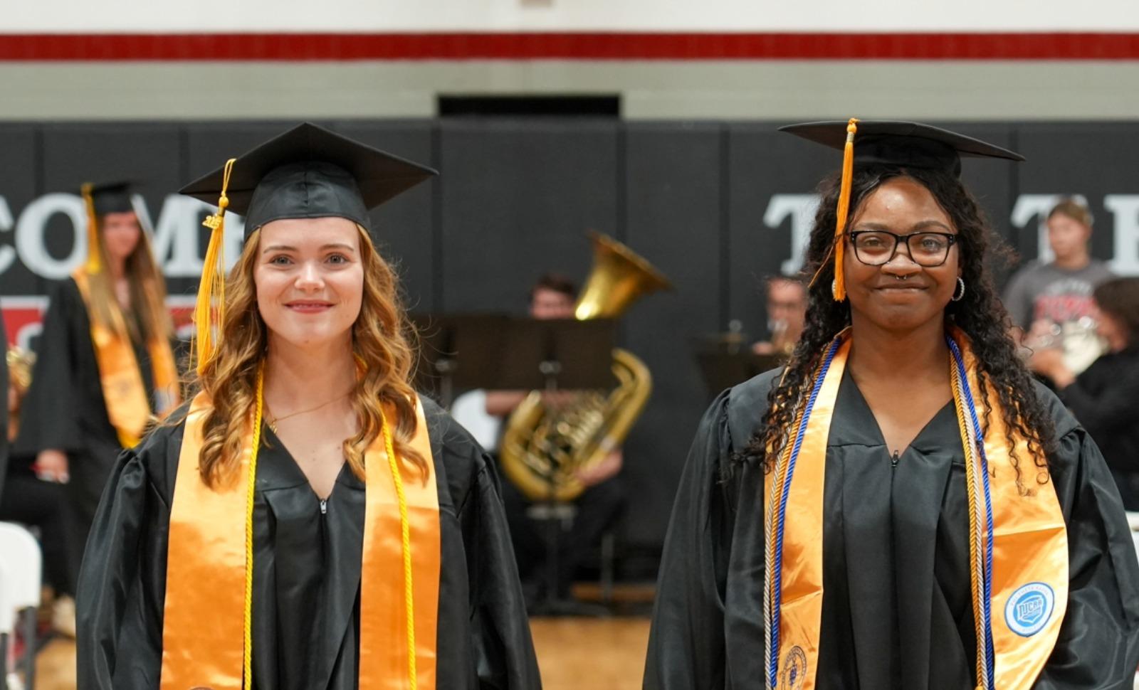Two Frontier Community College graduates walk down the aisle toward their seats during the college’s 2025 commencement ceremony.