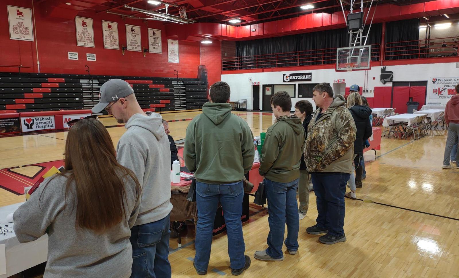 individuals line up at tables in the WVC gym talking to WVC representatives