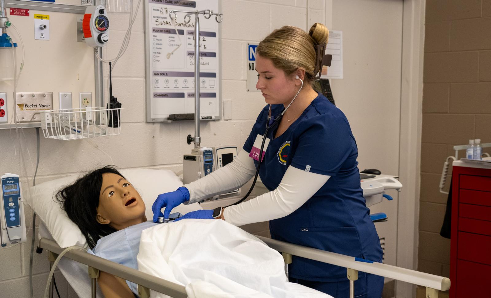 An LPN student takes vital signs on the patient manikin in the lab