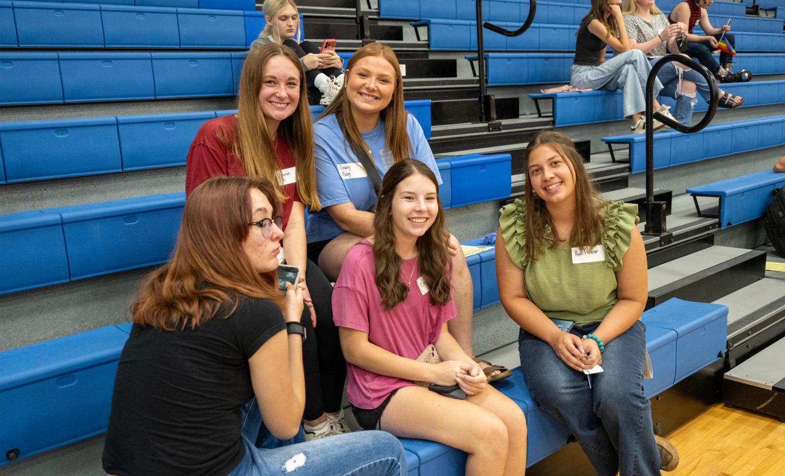 Smiling students sitting in the gym