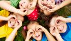 Children laying down in a circle using their hands as binoculars