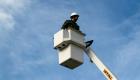 Student in bucket truck against a blue sky