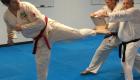 Man kicking a board in a martial arts class