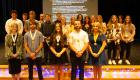 Lincoln Trail College Phi Theta Kappa officers stand in front with medals as new inductees pose behind them on stage during the induction ceremony, with a presentation screen in the background.
