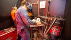 A welding student looks over her fabrication project at IECC's Welding Skills Competition