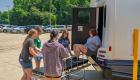 Students at the Pathways to Healthcare Camp participate in a simulated mass casualty incident, working together to safely transfer a mock patient from an ambulance to a stretcher in a parking lot.