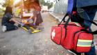 Paramedic worker carries red medical bag in direction of patient laying on gurnee with two other individuals assisting