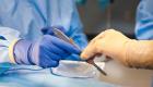 Close-up of a surgical technologist passing a scalpel to a surgeon in an operating room. Both wear protective gloves and sterile gowns, highlighting the teamwork and precision required in surgical technology careers.