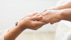 A younger person gently holding the hands of an older adult, symbolizing care, compassion, and support.