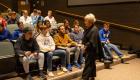 LTC President Tona Ambrose speaks with a group of students seated in a lecture hall during the ACES Competition at Lincoln Trail College. Students listen attentively, some taking notes, as Ambrose stands in front of them engaging in discussion.