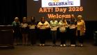 Celebrate Art! award winners stand on stage holding certificates during the 2026 event, posing with organizers in front of a large “Celebrate Art! Day 2026” screen.