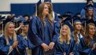 Student in cap and gown stands to be recognized during graduation.