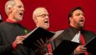 Three men are singing in the choir while holding music binders.